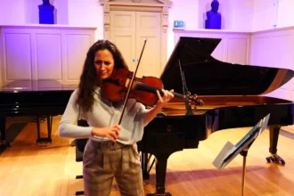 York Bowen: Φωτογραφία γυναίκας που παίζει Βιόλα μπροστά από ένα πιάνο, κλασική μουσική.